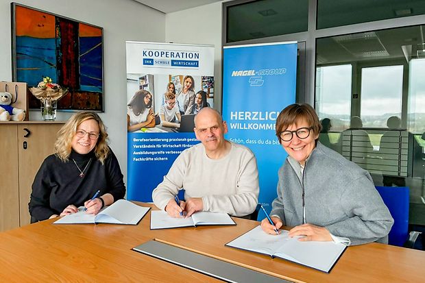Drei Personen unterzeichnen Dokumente f&uuml;r Kooperation von IHK und Nagel‑Group