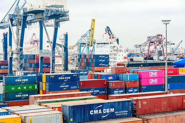 Containerterminals mit vielen bunten Frachtcontainern und Kr&auml;nen im Hafen.