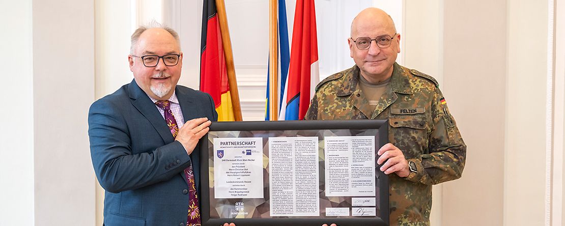 Ein Oberst der Bundeswehr &uuml;berreicht eine Partnerschaftsurkunde an den Gesch&auml;ftsbereichsleiter der IHK