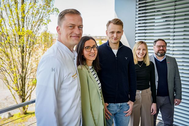 F&uuml;nf Personen stehen auf einem Balkon vor einem B&uuml;rogeb&auml;ude