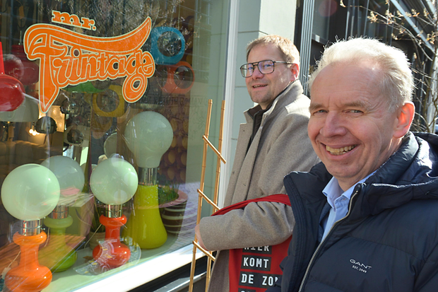 Zwei M&auml;nner stehen vor einem bunten Schaufenster. 