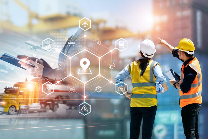 Zwei Personen mit Schutzhelmen vor einer Baustelle mit Kran und LKW sowie digitale Symbole