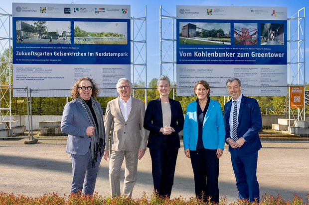F&uuml;nf Menschen stehen vor einem Baustellenschild. 