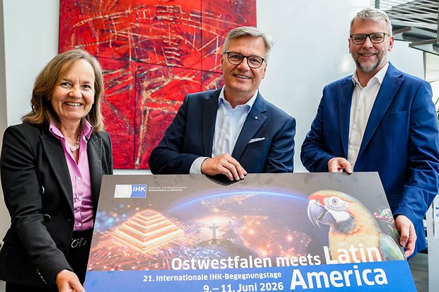 Drei Personen halten Plakat zu IHK-Event &bdquo;Ostwestfalen meets Latin America&ldquo;
