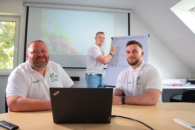 Drei M&auml;nner mit einem Laptop und einem Flipchart 