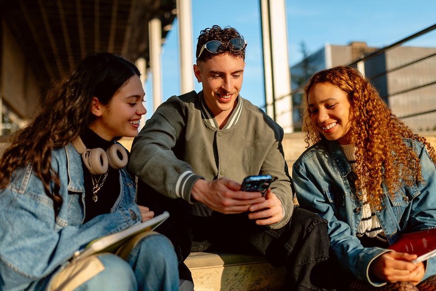 University students sharing a smartphone and smiling together