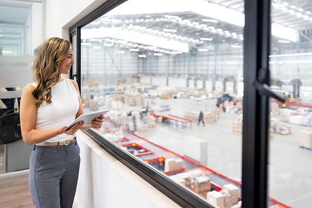 Businesswoman using a tablet while working from her office at a distribution warehouse