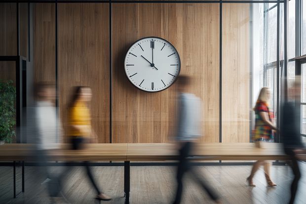 Menschen laufen an einer gro&szlig;en Uhr vorbei