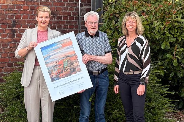 Zwei Frauen &uuml;bergeben eine Urkunde an einen Mann