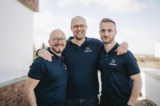 Drei fr&ouml;hliche M&auml;nner im Firmen-T-shirt
