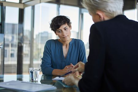 Zwei Gesch&auml;ftsfrauen gegen&uuml;ber am Schreibtisch gehen Unterlagen durch