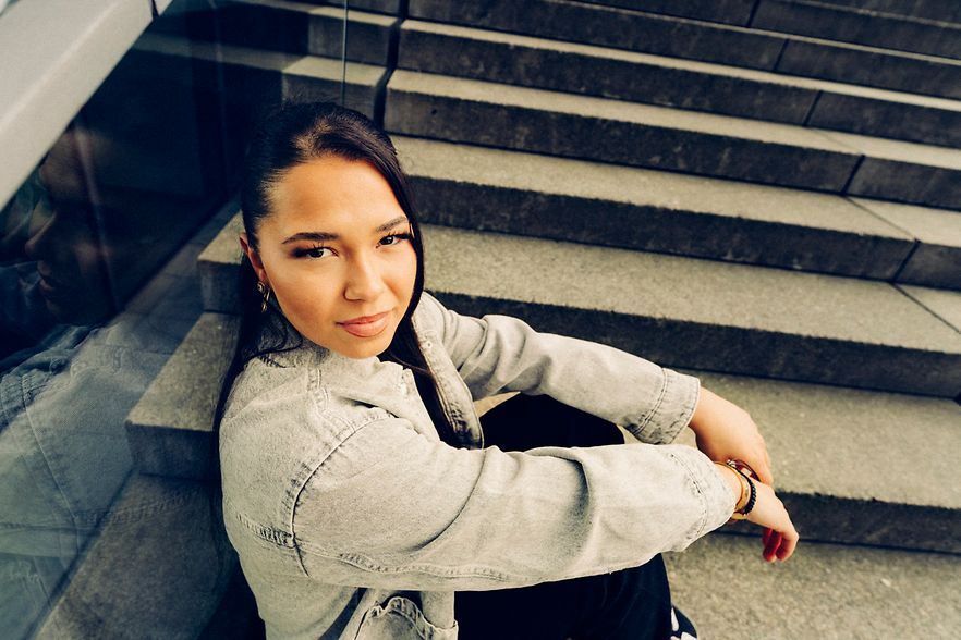 Eine junge Frau sitzt auf einer Treppe. 